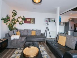 A living room with two sofas a coffee table a plant and a tripod lamp at Sea View in Penrhyn Bay