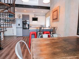 A kitchen with metal stools and wooden table near a spiral staircase at Sea View in Penrhyn Bay