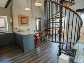 A kitchen and dining area with a spiral staircase and metal stools at Sea View in Penrhyn Bay