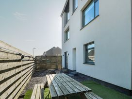 An outdoor area with a wooden picnic table and benches next to a building with windows and a wooden fence at Sea View in Penrhyn Bay