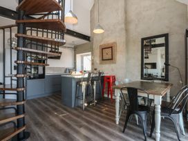 A kitchen and dining area with a spiral staircase and bar stools at Sea View in Llandudno
