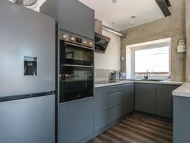 A kitchen with refrigerator, oven, sink and window at Sea View Llandudno
