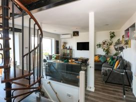 A living room with a spiral staircase and a tv at Sea View in Llandudno