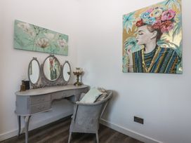 A vanity table with a mirror and lamp in a bedroom at Sea View in Llandudno
