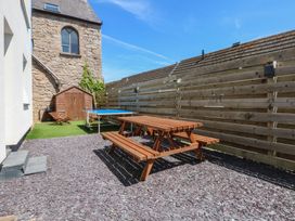 A garden with a picnic table, benches, and a shed at Sea View in Llandudno