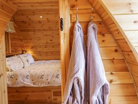 A bedroom with a bed and robes hanging at The Rhiw in Llanfair Caereinion