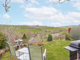 A garden with chairs and a table overlooking hills at The Rhiw in Llanfair Caereinion