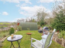 A garden with a green shed and seating area at The Rhiw in Llanfair Caereinion