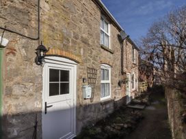 Exterior view of stone cottages with white doors and windows along a narrow path with bare trees at Northgate Cottage in Ysceifiog near Caerwys