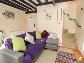 A living room with a gray sofa with green and patterned pillows and a purple throw near a staircase at Northgate Cottage in Ysceifiog near Caerwys
