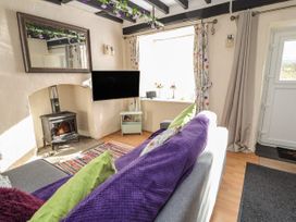 A living room with a wood stove television sofa with cushions and a window at Northgate Cottage in Ysceifiog near Caerwys