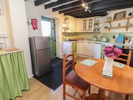 A kitchen with wooden table and chairs fridge stove and open shelves at Northgate Cottage Ysceifiog near Caerwys