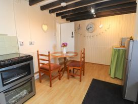 A kitchen with a round wooden table and two chairs a stainless steel stove and a refrigerator at Northgate Cottage in Ysceifiog near Caerwys