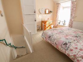 A bedroom with a bed a wooden dresser and floral curtains at Northgate Cottage in Ysceifiog near Caerwys