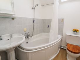 A bathroom with a bathtub shower sink and toilet with wooden seat at Northgate Cottage in Ysceifiog near Caerwys