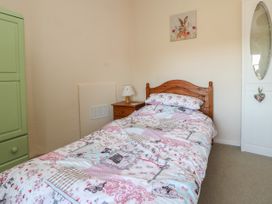 A bedroom with a single bed a bedside table with a lamp a green wardrobe and a wall painting of a rabbit at Northgate Cottage in Ysceifiog near Caerwys