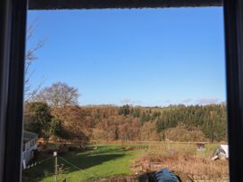 A grassy backyard with trees and garden plots viewed through a window at Northgate Cottage in Ysceifiog near Caerwys