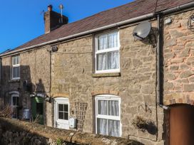 Stone built row of houses with white framed windows and doors under a blue sky at Northgate Cottage in Ysceifiog near Caerwys