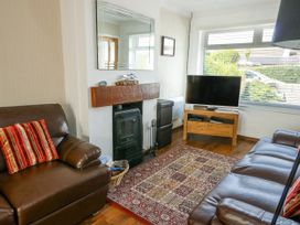 A living room with a fireplace and a television at Fern Hill Cottage in Newborough