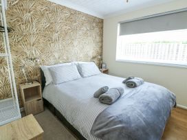 A bedroom with a bed and nightstand at Fern Hill Cottage in Newborough