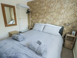 A bedroom with a bed and a mirror at Fern Hill Cottage Newborough