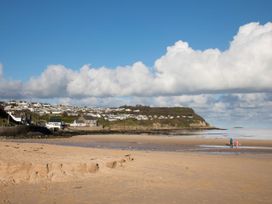 A beach with people walking and houses in the background at Hunters Cottage Benllech