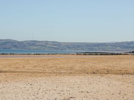 A beach with sand and water at Hunters Cottage in Benllech
