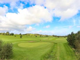 A golf course with a putting green and trees at Big Azzles in Benllech