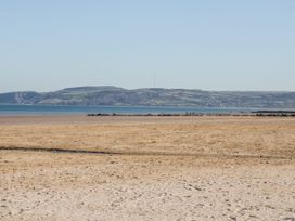 A beach with water and hills in the background at Big Azzles in Benllech
