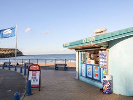 An ice cream kiosk with flags and benches at the beach at Big Azzles in Benllech