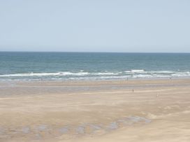 A beach scene with sand and ocean at Big Azzles in Benllech