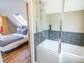A bathroom featuring a bathtub and shower with a bedroom view at The Coach House in Chacombe