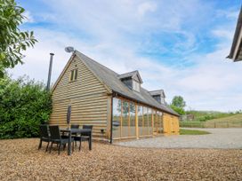 An outdoor area with a table and chairs in front of a wooden house at The Coach House in Chacombe
