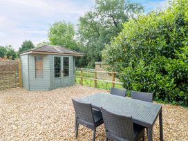 A garden with a table and chairs next to a shed at The Coach House in Chacombe