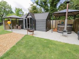 A garden with a shed, outdoor seating, and a spa at Acorn Lodge At Bridge Lake Farm & Fishery Chacombe