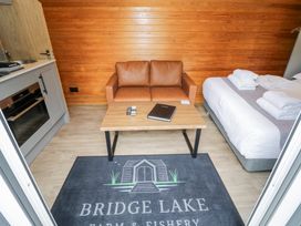 A living room with a sofa and kitchen unit at Acorn Lodge At Bridge Lake Farm & Fishery Chacombe