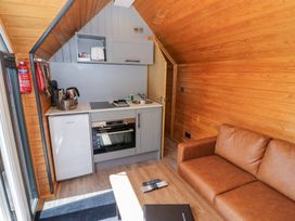 A kitchen with appliances and a sofa at Acorn Lodge At Bridge Lake Farm & Fishery Chacombe