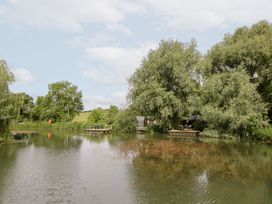 A pond with trees and dock at Acorn Lodge At Bridge Lake Farm & Fishery Chacombe