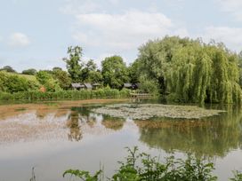 A pond with lily pads and cabins at Acorn Lodge At Bridge Lake Farm & Fishery Chacombe