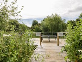 A deck with a bench and signs for floating pontoons at Acorn Lodge At Bridge Lake Farm & Fishery, Chacombe