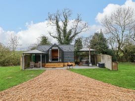A cabin with outdoor seating and a fire pit at Acorn Lodge At Bridge Lake Farm & Fishery Chacombe
