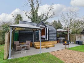 A cabin with outdoor seating and fire pit at Acorn Lodge At Bridge Lake Farm & Fishery in Chacombe