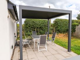 A patio with a table and chairs under a pergola at Pen Y Cefn