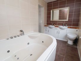 A bathroom with a bathtub, sinks, and a toilet at Castellolwg