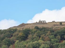 Ruins on a hillside with trees and a blue sky at Castellolwg