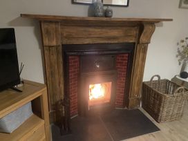 A fireplace with a stove and wooden mantel in the living room at Awelfa, Newport, Pembrokeshire