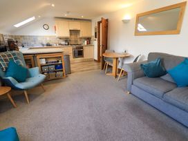 A living room with a kitchen area and furniture at High Dow Crag in Coniston
