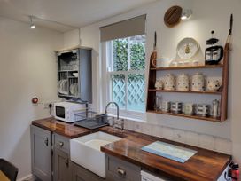 A kitchen with sink and shelf holding dishes at Millgate Cottage in Conwy