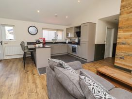 A kitchen with barstools and a sofa at Barn Owl in Otterburn