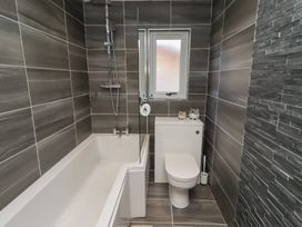 A bathroom with a bathtub, toilet, and window at Barn Owl in Otterburn